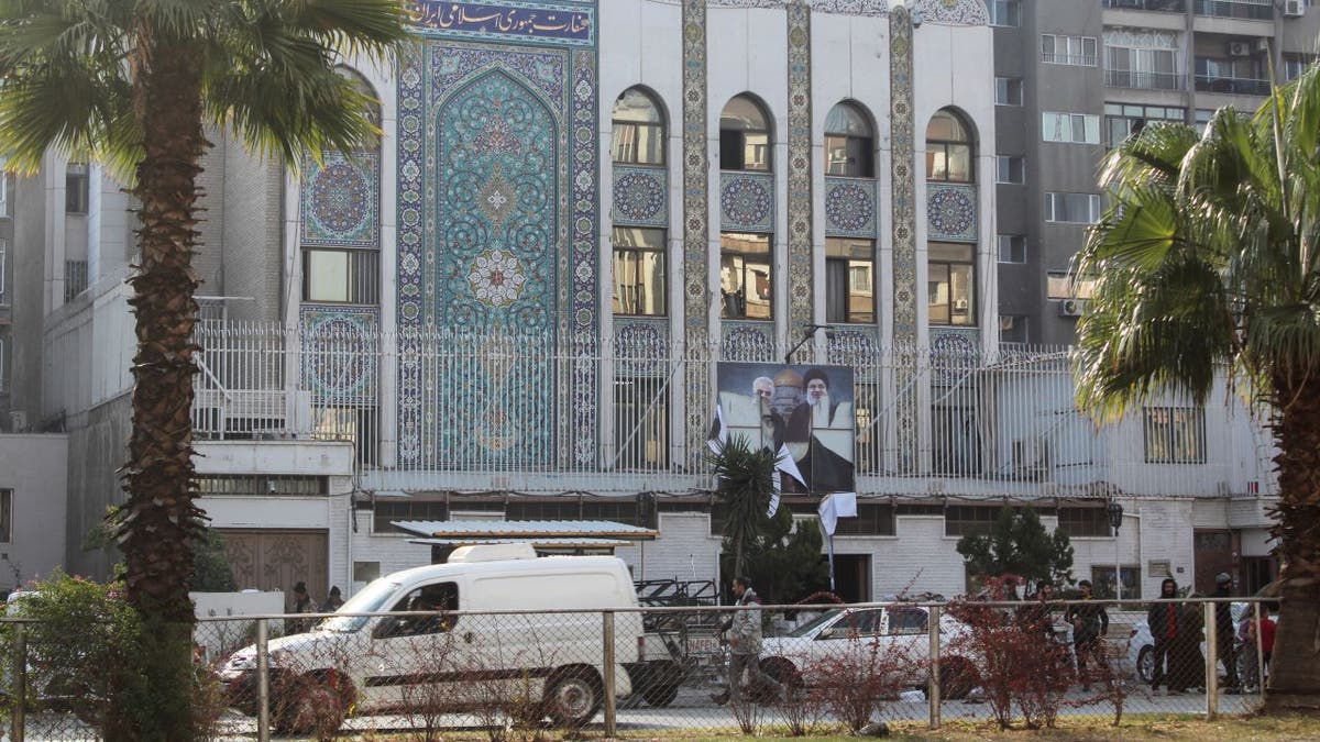 Rebel fighters stand near the Iranian Embassy with a torn poster of Hezbollah leader Sayyed Hassan Nasrallah and late Iran's Revolutionary Guards' top commander Qassem Soleimani after Syrian rebels announced that they have ousted President Bashar al-Assad, in Damascus, Syria, on Dec. 8, 2024.