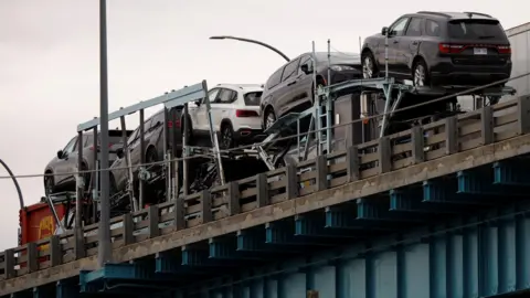 Reuters New SUV vehicles cross a bridge from Canada into the United States