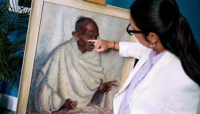 Rhyanon Demery, Bonhams Head of Sale for Travel and Exploration, points out the spot where the now-restored painting by British-American artist Clare Leighton of Indian independence leader Mahatma Gandhi was once damaged at Bonhams auction house in London on June 9, 2025. — AFP